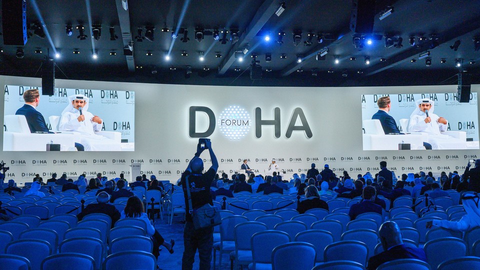 Photograph of a large auditorium at the Doha Forum with two speakers on stage
