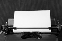 A black-and-white image of a blank sheet of paper in a typewriter