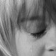 Cropped black-and-white close-up image of a child crying