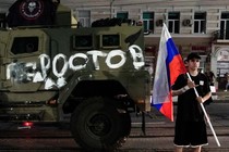 Photograph of a man holding aRussian flag next to an army tank
