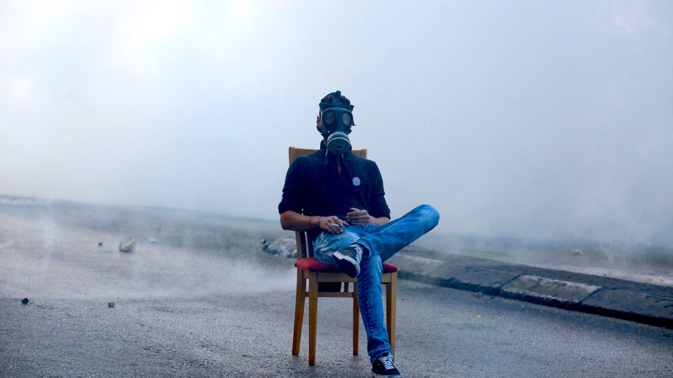 A Palestinian protester sits in the middle of a road as Israeli troops fire tear gas during clashes in the West Bank in 2015.