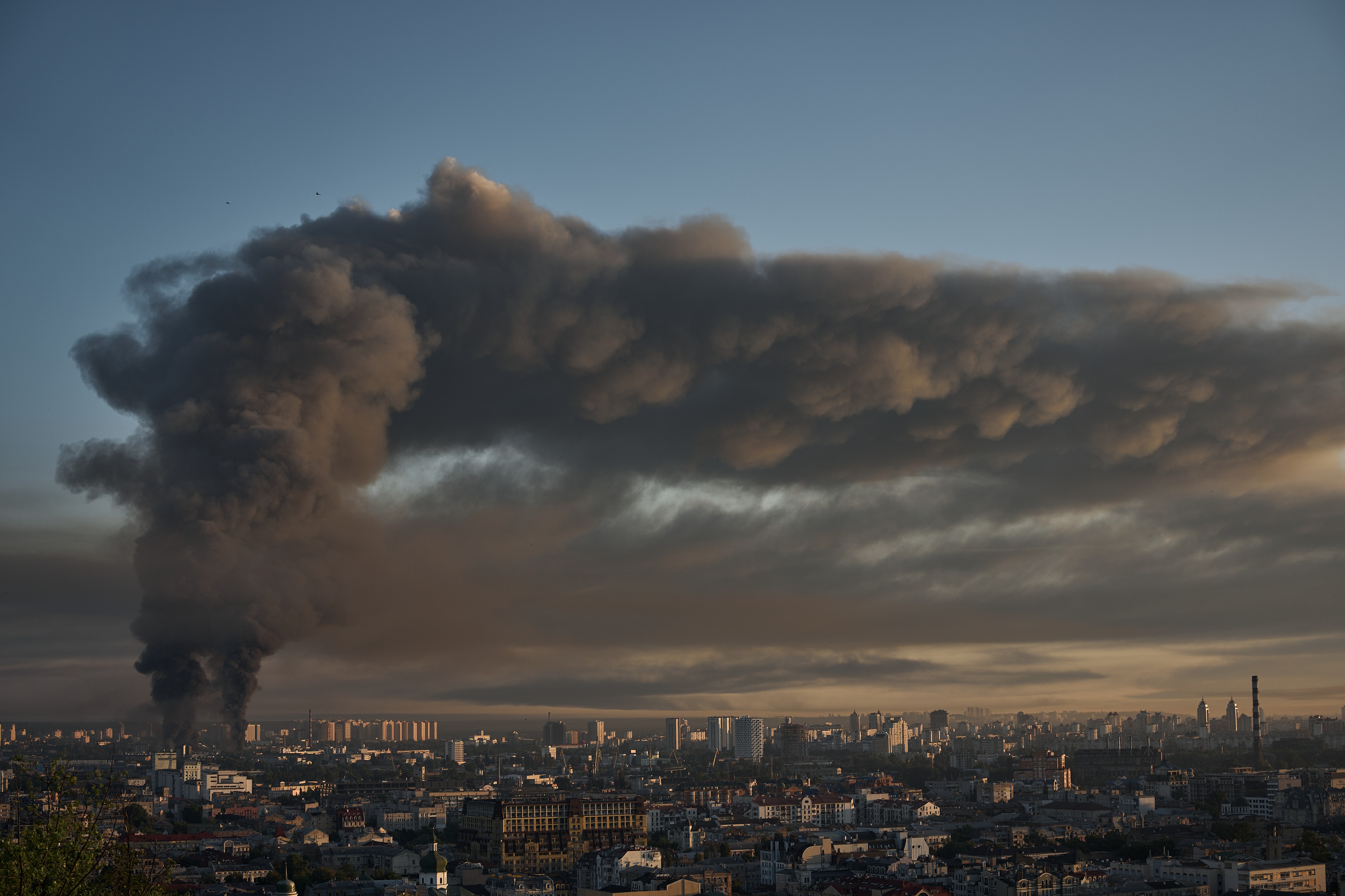 Smoke from a large fire rises and spreads over a city.