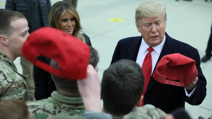 Donald Trump holds a cap while visiting U.S. troops at Ramstein Air Base in Germany on December 27, 2018.