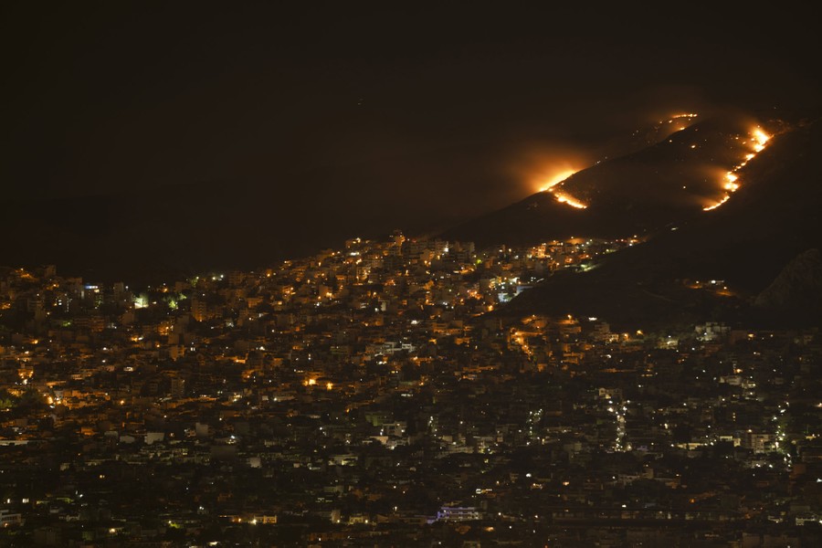 A night view of a hillside, its lower slopes filled with houses, its empty upper slopes burning