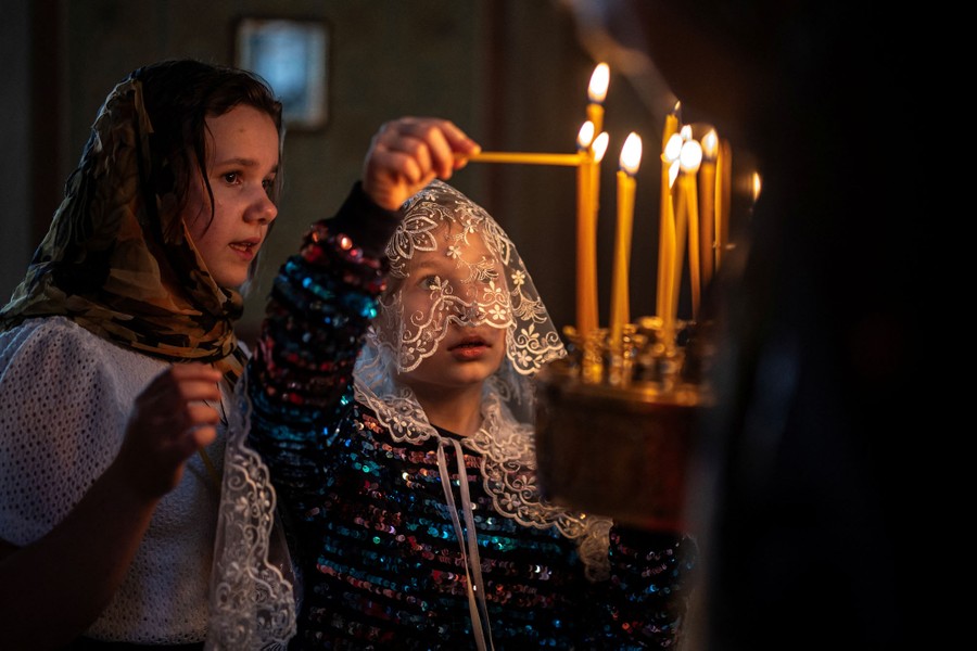 Two children light candles in a church.