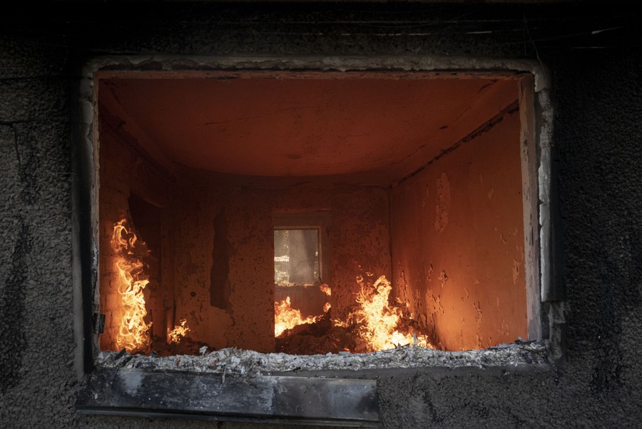 The burning interior of a building framed by a window