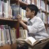 A boy looks through the shelves at a library.