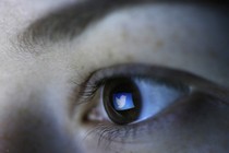 The Twitter logo is reflected in the pupil of a brown eye.