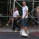 A person rides a one-wheeled hoverboard down a street.