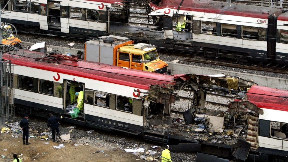 Railway workers remove debris from the wreckage of a bombed public train in Madrid on March 12, 2004.