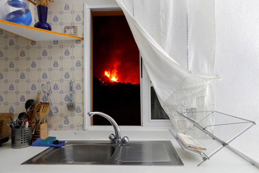 An eruption is seen through the window of a kitchen.