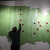 A man reaches up to touch a map of the United States decorated with red and blue stars.