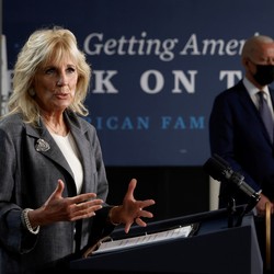 Jill Biden speaks at the podium at Tidewell Community College with Joe Biden in the background