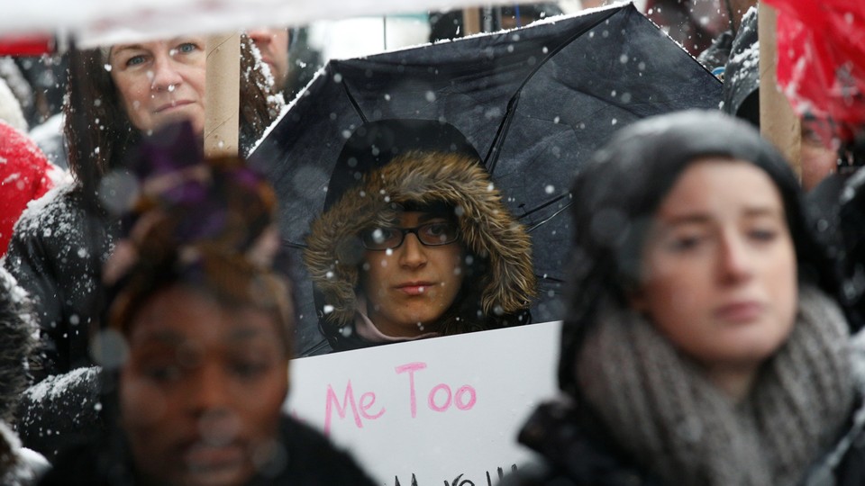 A woman holds a "Me Too" sign. 