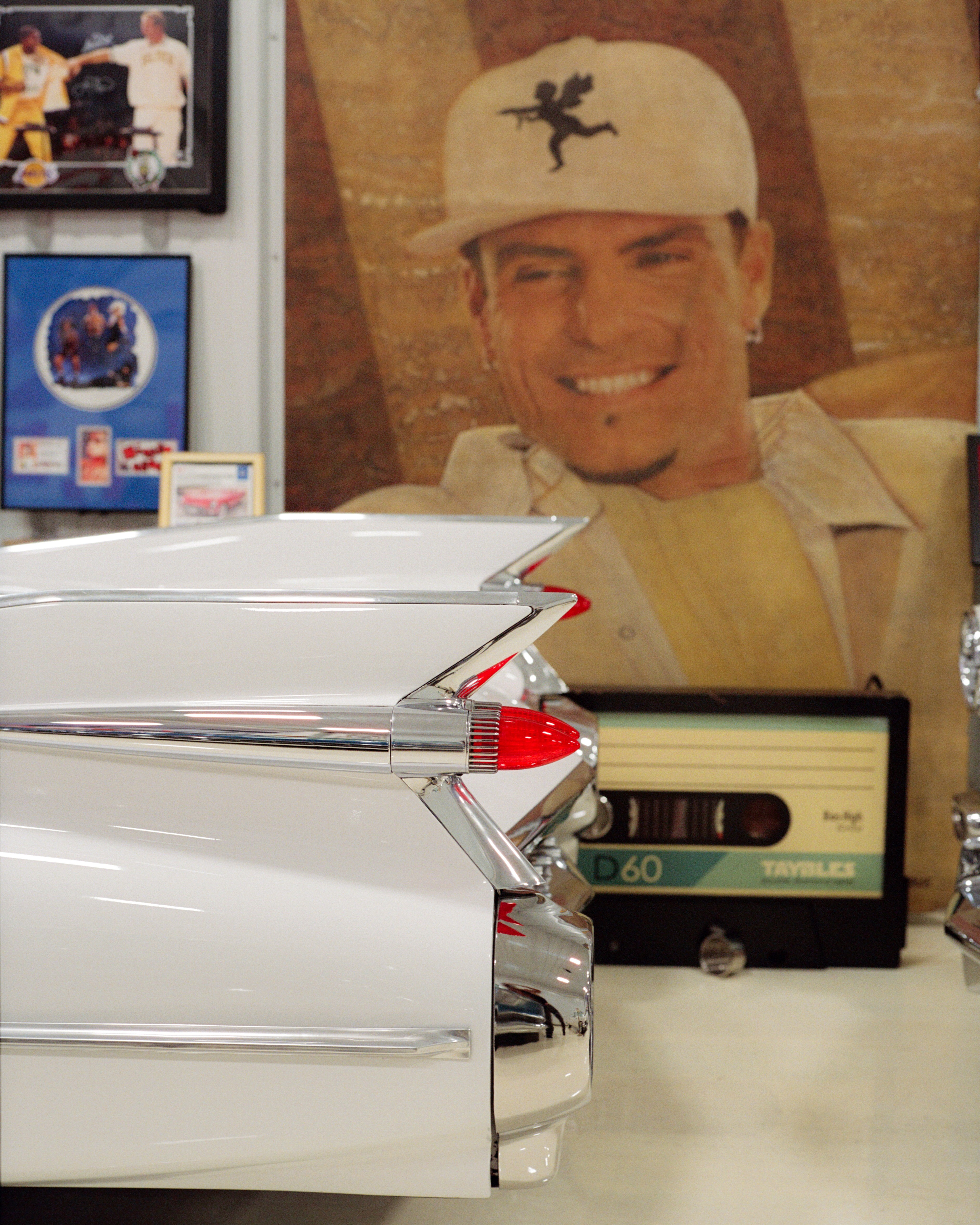 The back of a vintage vehicle and a poster of Vanilla Ice