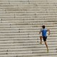 A man in athletic clothing runs up a long flight of stairs