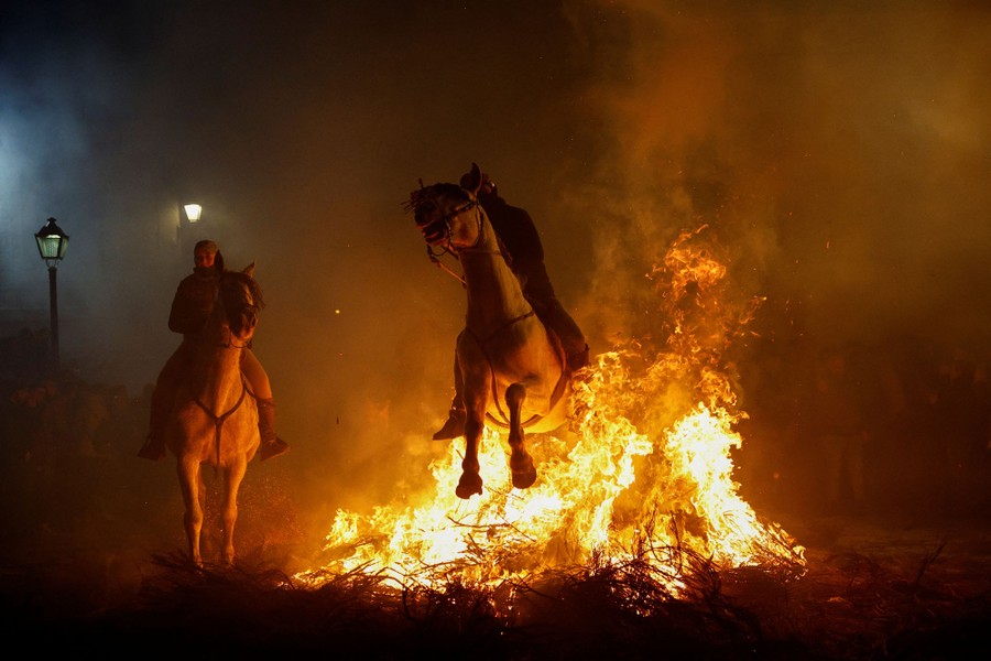 A rider on a horse leaps through a large bonfire.