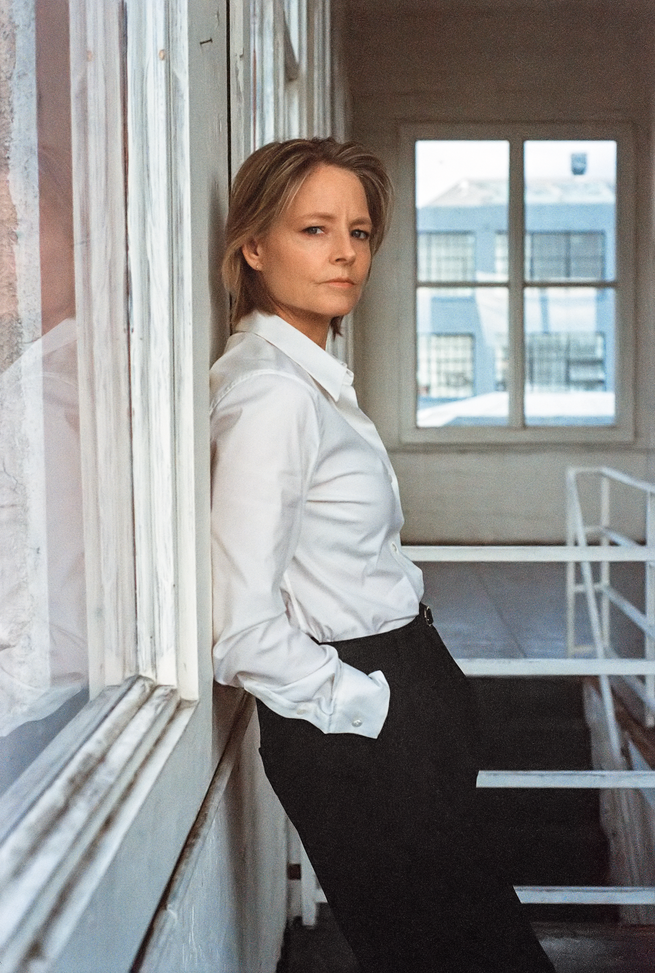 photo of woman in white shirt and black pants leaning against wall