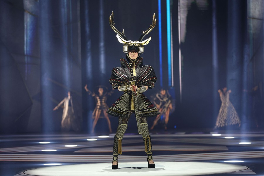 A model wears a samurai-themed costume with an antlered helmet.