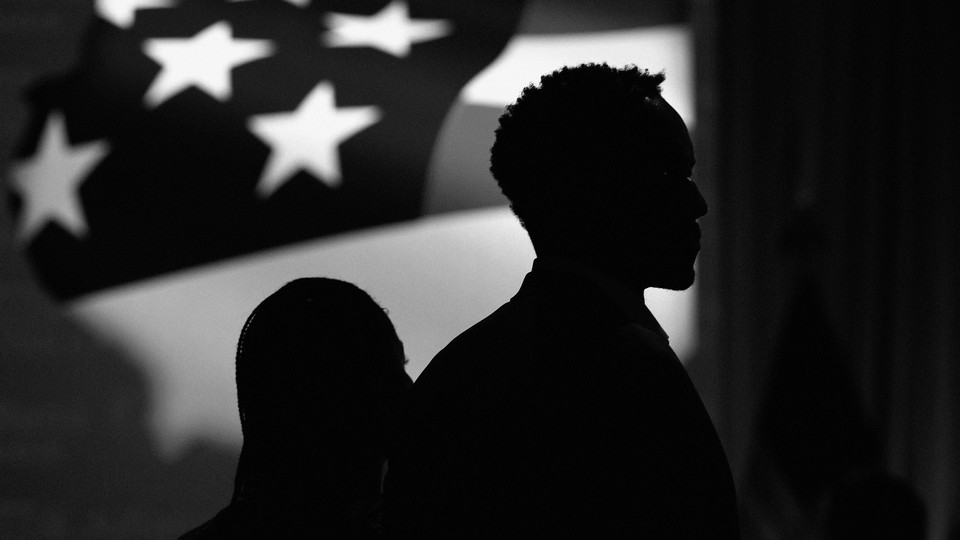 A figure silhouetted against an American flag
