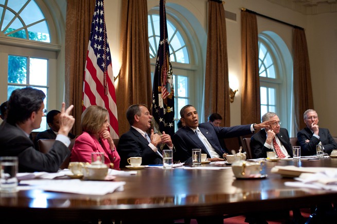Obama negotiating in a crowded conference room.