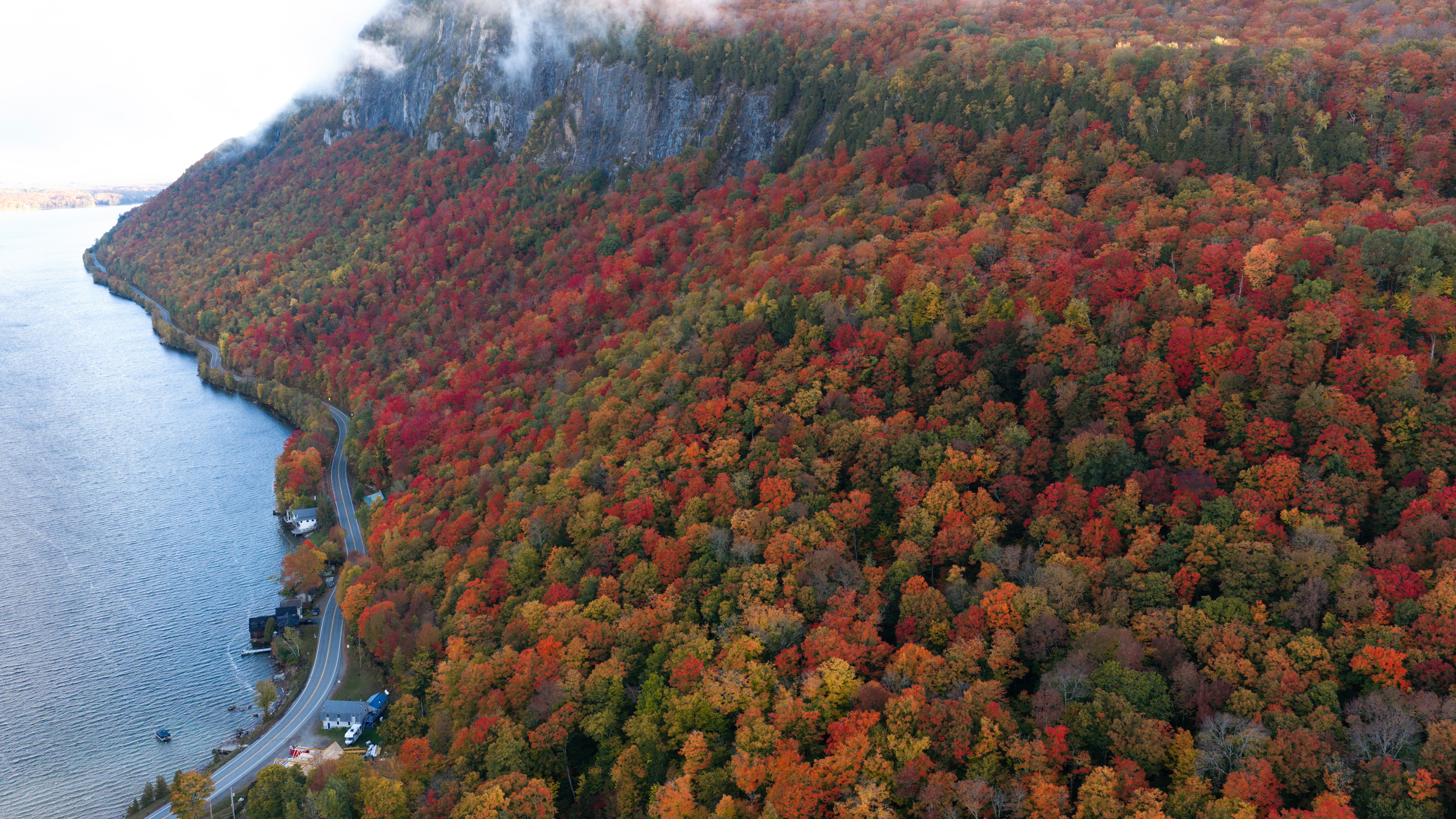 An aerial view of a wide mountain slope covered in fall-colored trees