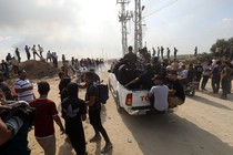 A desert road full of people and a packed Toyota truck