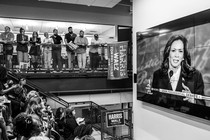 A group of people watch Kamala Harris debating Trump.