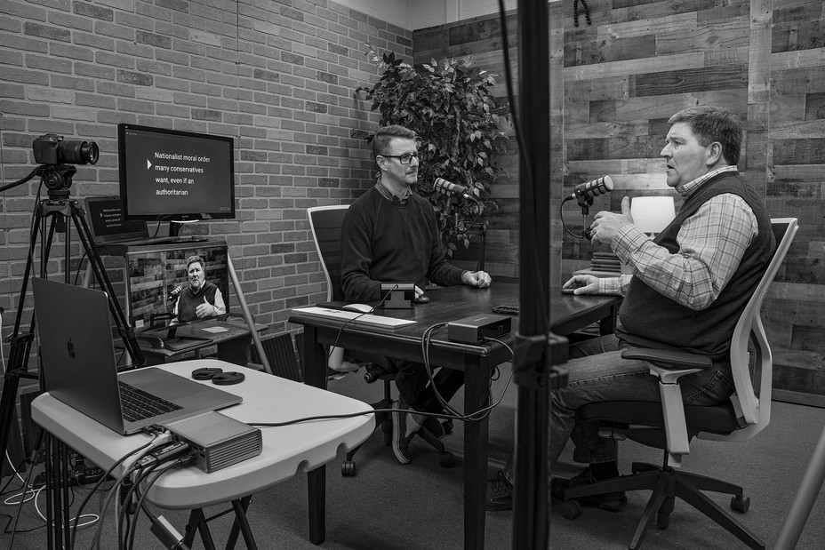 photo of podcast studio with two men sitting at table with mics and video equipment