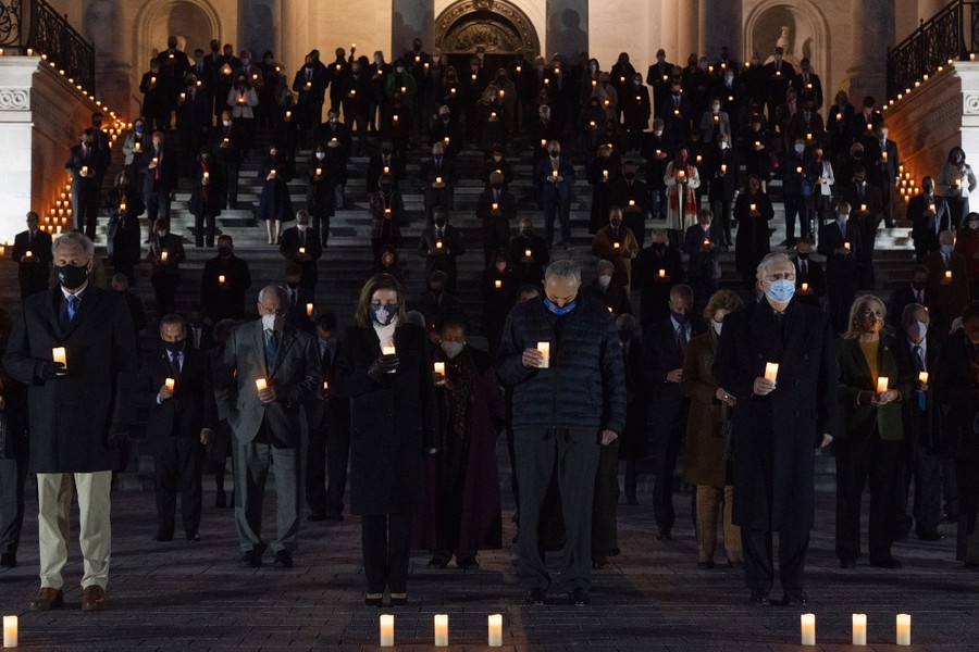 Members of the House and the Senate stand on steps at night, holding candles.