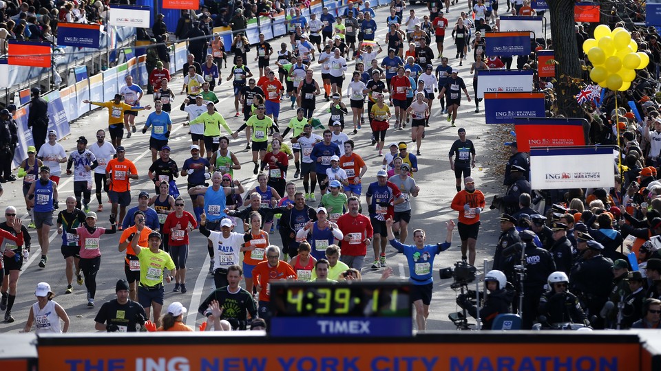 Runners approach the New York City Marathon finish line, where a clock reads 4:39:11
