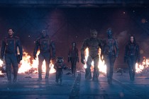 The Guardians of the Galaxy walking toward the camera with flames in the background