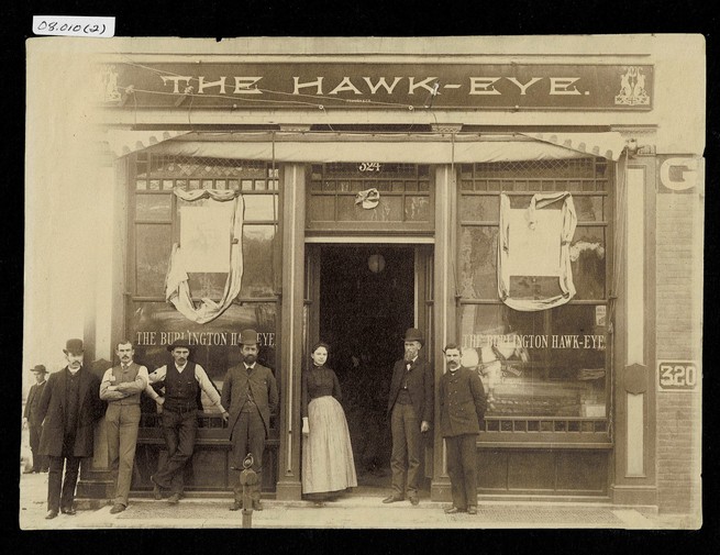 Old photograph of people standing in front of the former Hawk Eye building.