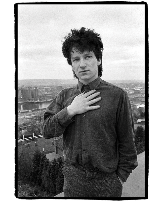 black-and-white photo of Bono with hand to chest