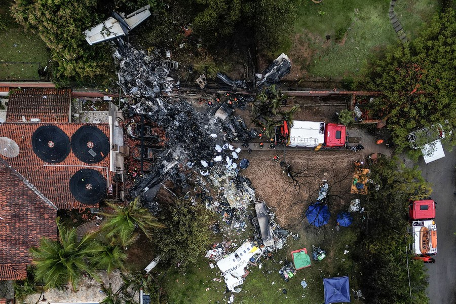 An aerial view of the wreckage of an aircraft beside a house and trees