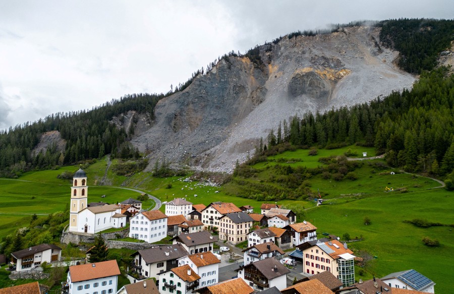 A view of a Swiss village standing beneath a crumbling mountainside.