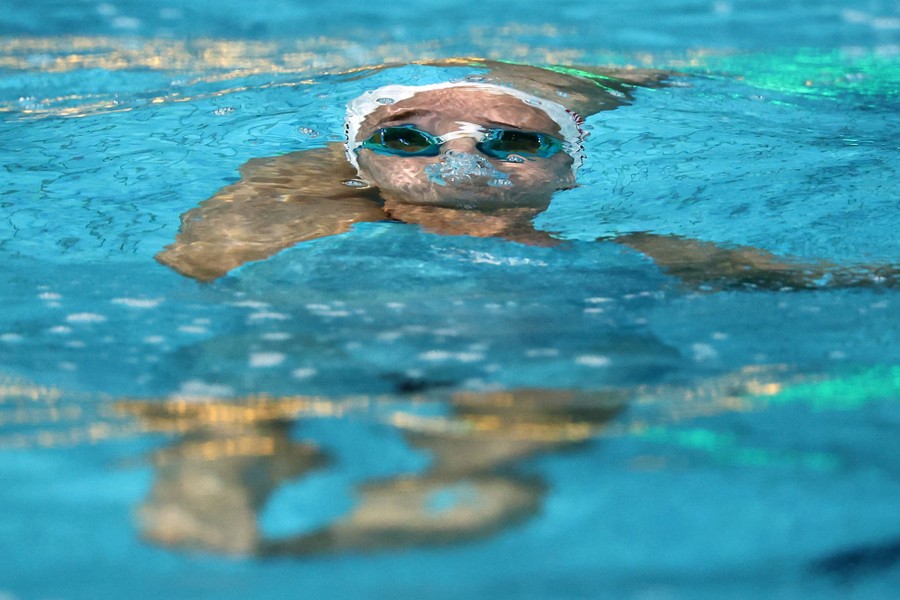 A swimmer competes, passing by underwater in a pool.