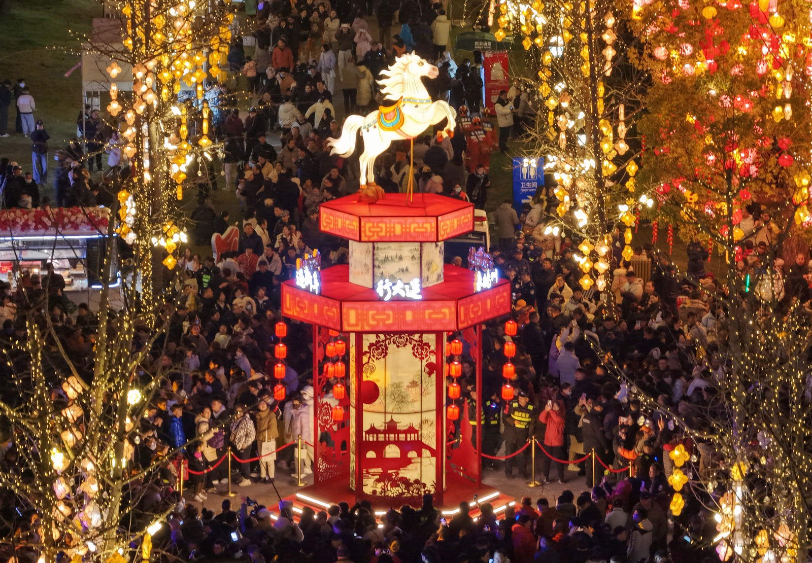 Visitors gather around a horse-themed lantern installation in a square.