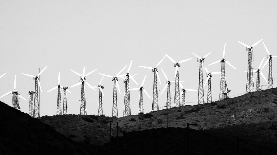 A black-and-white photo of wind turbines along a hillside