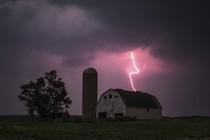 An image of a barn, with lightning striking over it. 