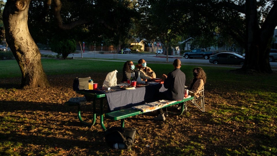 A family eating holiday dinner outside.