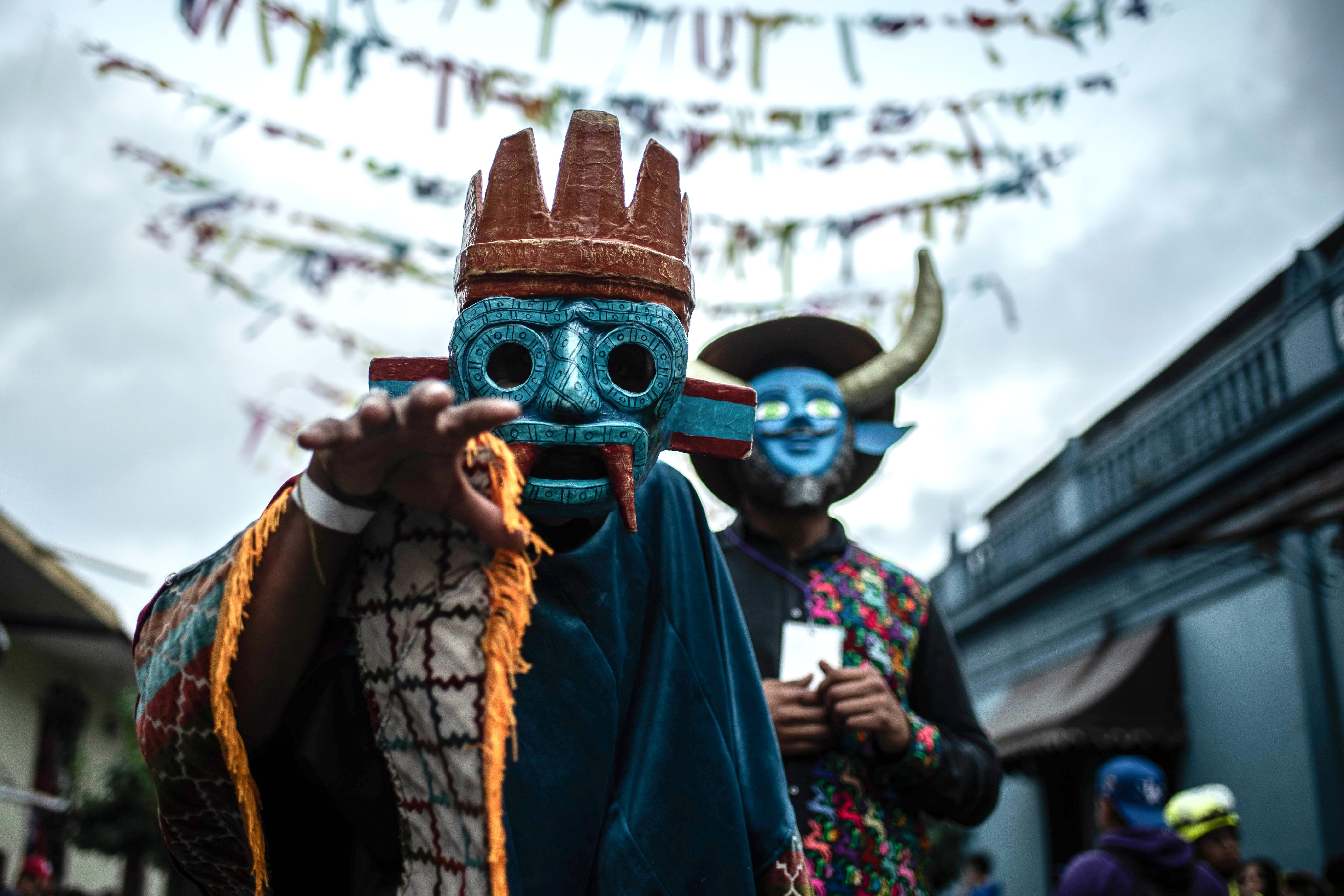 Dancers wearing frightening masks pose during a festival.
