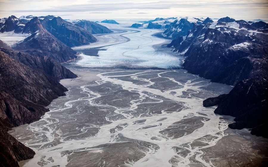 An aerial view of a glacier and a wide valley below it