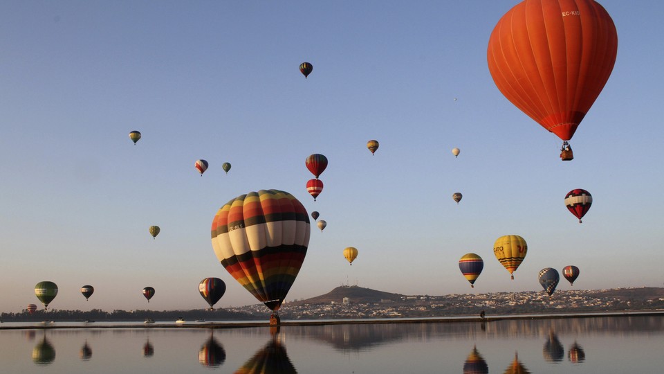 Hot-air balloons and their reflections along a coastline 