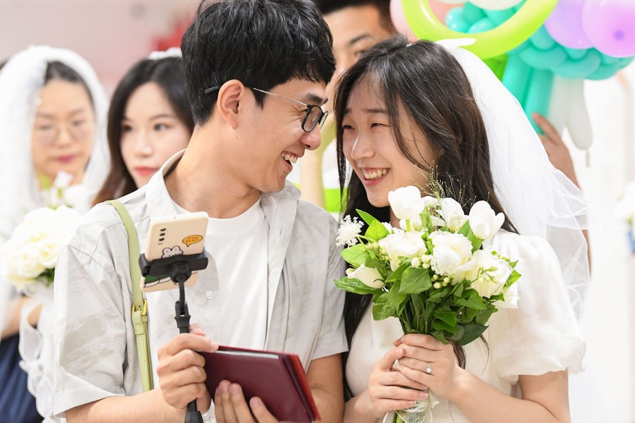 A newlywed couple smile at each other.