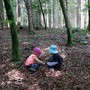 Two kids play in a forest. 
