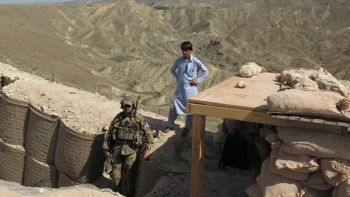 A U.S. soldier stands at a post in Nangarhar province alongside an Afghan civilian.