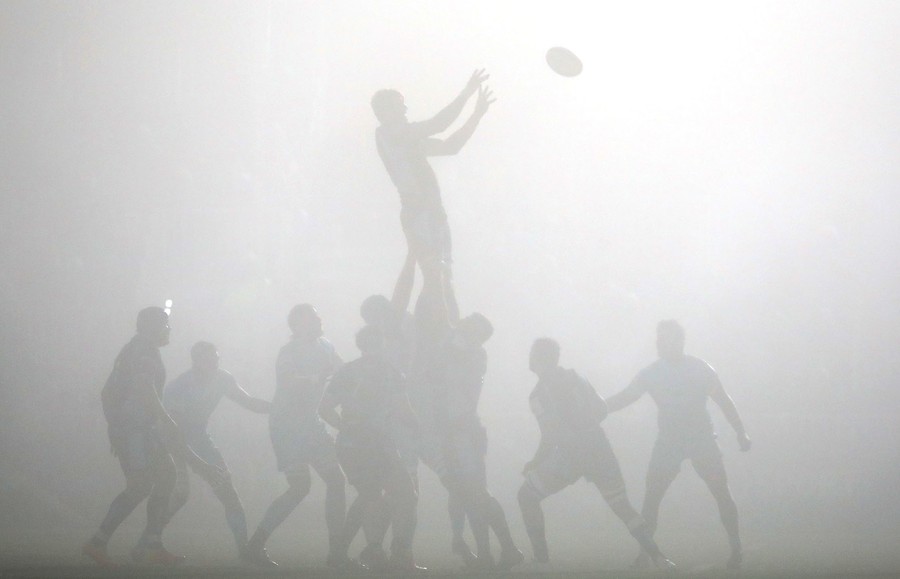 Rugby players play in fog.