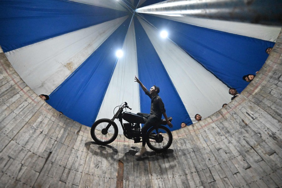 A motorcycle rider rides sideways on the inside of a six-meter-high circular wall.