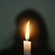 A photograph showing a candle in front of a silhouette of a person